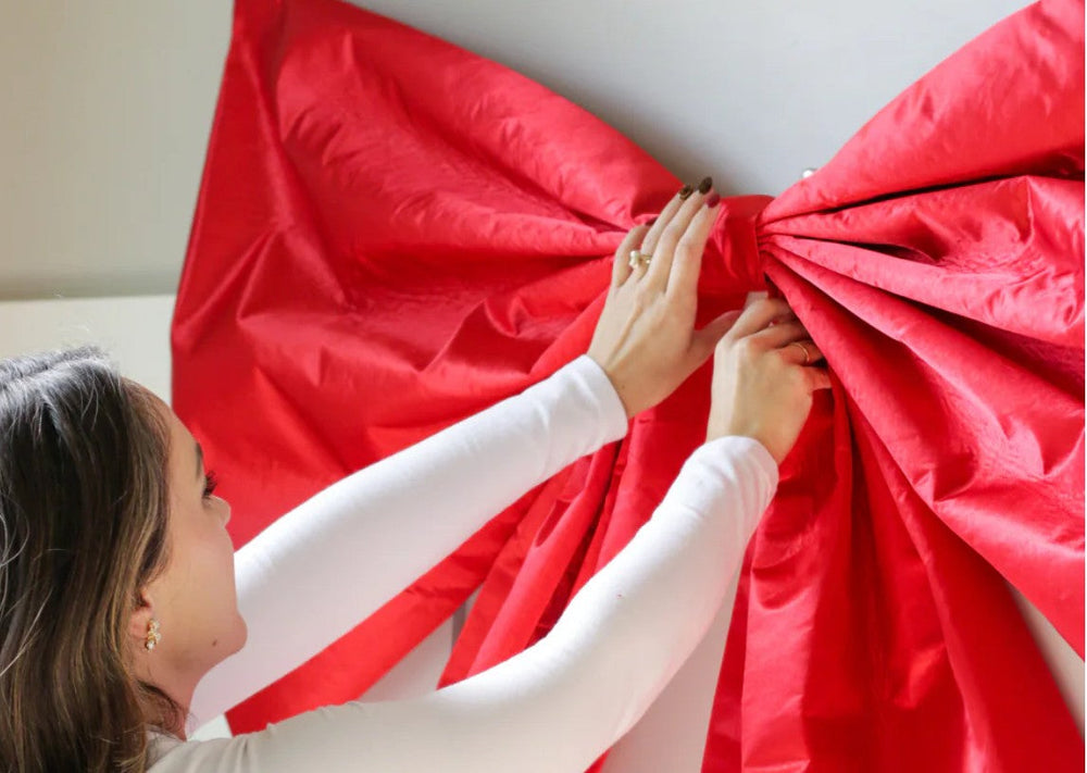 red fabric bow made with Aleene's glue being attached to the wall